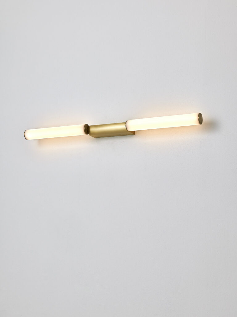 <p></noscript>Signal is a creation signed by the famous and late French designer Pauline Deltour. Inspired by the neon of yesteryear, the designer sought to change the perspective of the tube to make it innovative and elegant. The originality of this linear wall lamp lies in the off-axis light source of its brass support, giving it a very contemporary design. Its great sobriety makes it possible to place this single or double decorative luminaire just as well in a bedroom as a bedside light, in a hotel room corridor in vertical repetition or in a living room near a reading corner. Signal illuminates with its harmonious light and casually blends into the decoration of the room in which it is located.</p>
<p>The Signal linear wall light is available in 6 sizes (345 mm, 445 mm, 545 mm, 520 mm, 720 mm and 920 mm) to meet all the needs of your customers’ interior projects and always in the usual finishes, in satin and polished decor. It is supplied with its LED light source, 2700 Kelvins and finally comes in several pendants and floor lamps, to be discovered too.</p>
